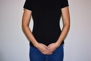 Woman holding hands on lower abdomen, symbolizing period pain, stomach ache or bladder discomfort. Concept of cramps, health issues, digestion problems and discomfort in women.