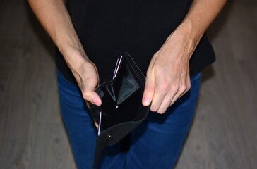 Close-up of a woman holding an open empty wallet, symbolizing lack of money, personal budget problems, financial crisis or poverty. Concept of overspending and saving challenges.