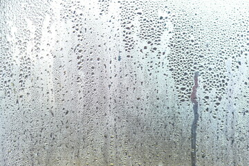 Foggy window with water droplets running down the glass.