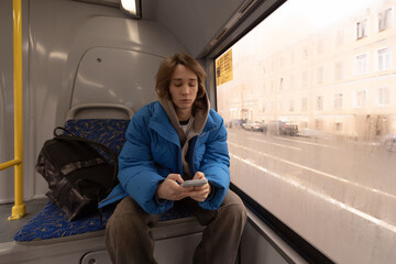 A young man on a city bus, a guy in public transport with a mobile phone in his hand