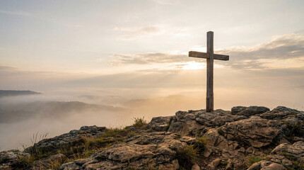 Wooden cross on rocky hilltop at dawn with misty valley and soft sunrise light, Christian symbol of faith on mountain peak, peaceful spiritual landscape background with copy space for religious and in