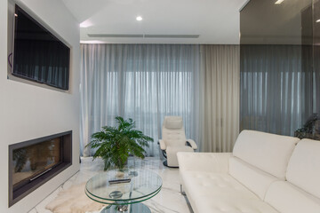 Modern living room with sleek white furniture and elegant decor overlooking a scenic view