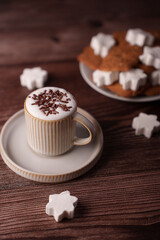 a cozy coffee cup topped with chocolate shavings sits beside a plate of star-shaped cookies, creating a warm and inviting setting on a rich wooden surface, aesthetic, calm, presentation, arrangement