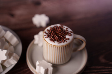 cozy scene of a creamy hot chocolate with chocolate sprinkles in a textured mug on a wooden table, surrounded by star-shaped marshmallows evoking a warm, inviting atmosphere, soft, focus, moment