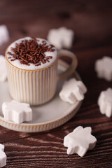 warm ceramic mug of hot chocolate with rich foam, topped with chocolate sprinkles, surrounded by white marshmallows on dark wooden surface for cozy atmosphere, intense, aroma, wrapped, festive