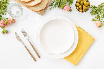 Festive table setting with empty plate, cutlery and napkin - bread and olives for dinner, flat lay. Top view