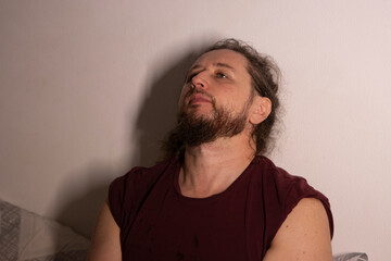 Young man looking up with pensive expression against wall