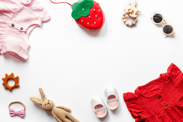 Flat lay frame of summer clothes for baby girl - pink and red cotton muslin dress with accessories, top view