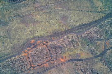 Aerial top down view of square military defensive positions dug around trees. War zone earthworks and muddy logistics route network background.