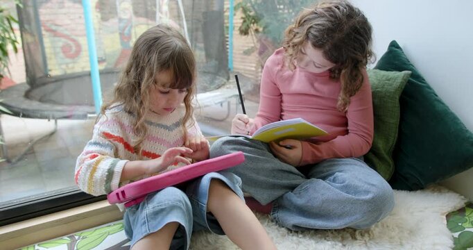 Sisters sharing Digital tablet in cozy corner at Home