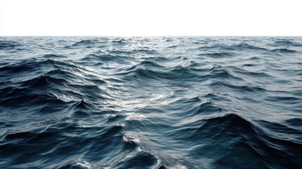 Waves rise and fall on the surface of water in the open sea. Sunlight reflects off the water creating a dynamic scene of natural movement.
