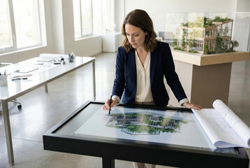 Female architect designing sustainable building on interactive table