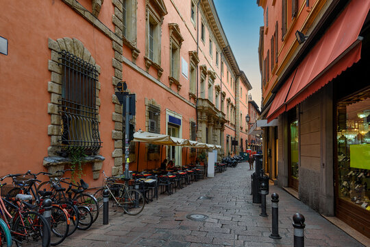 Old narrow street with tables of restaurant in Bologna, Emilia Romagna, Italy. Architecture and landmark of Bologna. Cityscape of Bologna.