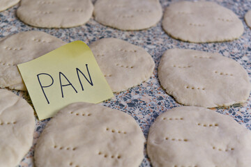 Raw dough bread being prepared, with the word PAN on a post-it note, highlighting the baking process.