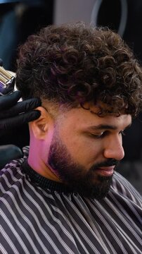 Professional barber using electric clipper to create a fade haircut