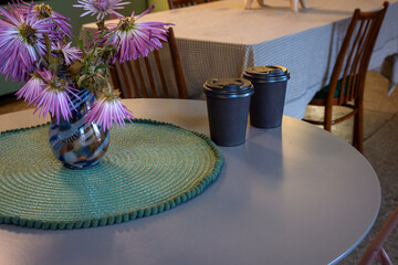 Brown closed takeaway coffee cups on a table in a cozy cafe.