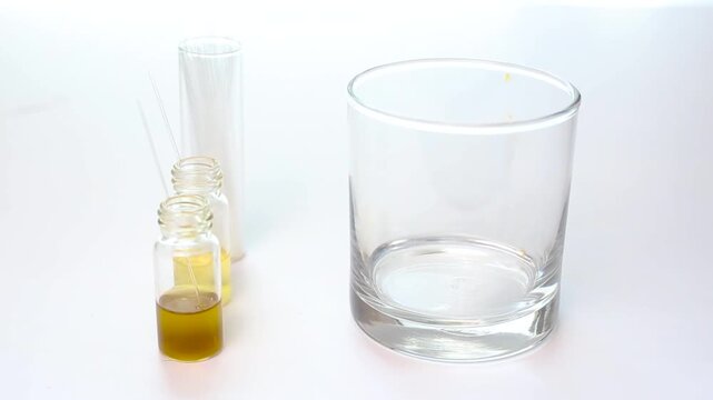 A scientist uses forceps to place a spotted Thin Layer Chromatography (TLC) plate into a solvent tank to initiate chemical component separation analysis.
