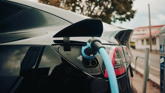 Close up view of a charging plug connected to a sleek black electric car