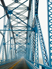 Going over a two-lane blue truss bridge on a foggy day.