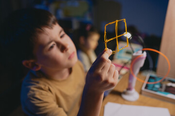 Young boy carefully constructs intricate wire art beneath lamp glow