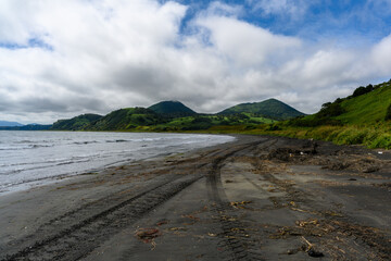 A serene beach scene unfolds with gentle waves lapping at the dark sand