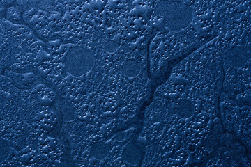 Dark blue embossed cardboard texture background with an abstract bubble relief pattern. Macro closeup of a rough and uneven paper surface. Photo