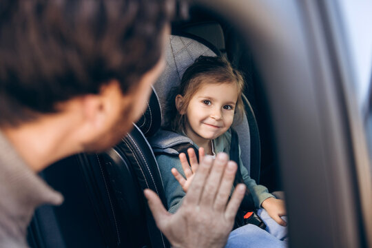 Fototapeta Father and daughter doing high-five in car seat