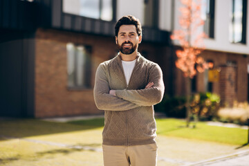 Happy handsome man businessman posing in front of modern suburban house