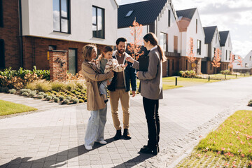 Happy, smiling family receiving keys from real estate agent to new home