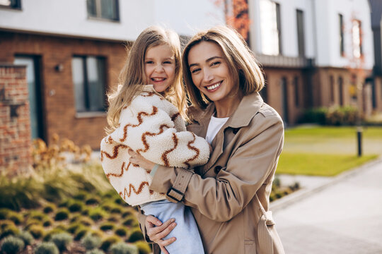 Smiling beautiful mother and daughter embracing and smiling outdoors