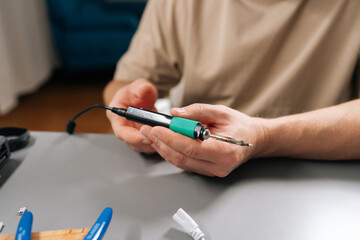Close-up of technician soldering wires for repair, fixing cable connection with soldering iron, engaging in electronics hobby, preparing components for diy project, working on circuit board at home.
