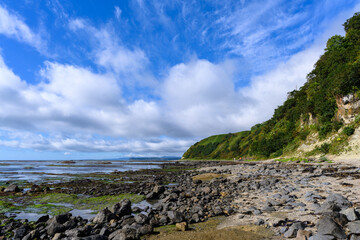 Waves crash gently against the rocky shoreline in Russia on a sunny day