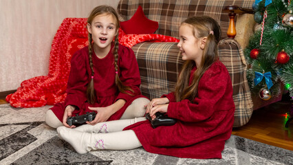 Happy girls sisters laugh and play video games together using a video game console n christmas holiday