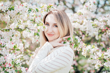 Blonde woman enjoying spring blossoms, peaceful moment in blooming cherry garden, seasonal beauty, floral fashion concept, nature appreciation, feminine serenity, romantic outdoor lifestyle