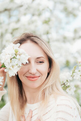 Blonde woman enjoying spring blossoms, peaceful moment in blooming cherry garden, seasonal beauty, floral fashion concept, nature appreciation, feminine serenity, romantic outdoor lifestyle