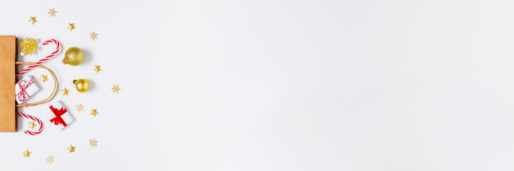 Gift bag with golden decorations, candy canes and tiny presents on white background, ideal for holiday banners, festive sales, winter marketing and Christmas promo layouts. Flat lay, copy space