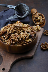 Peeled walnuts in wooden bowl isolated on wooden background. Top view.