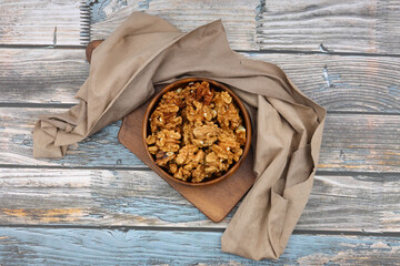 Peeled walnuts in wooden bowl isolated on wooden background. Top view.