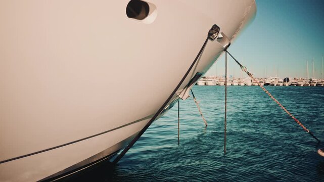 Detailed shot of a yacht's bow secured with ropes and chains over turquoise water
