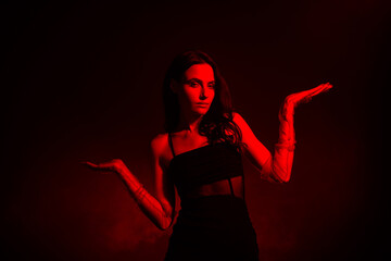 Fashionable young woman in red lighting with mysterious poses, showcasing fashion, sensuality