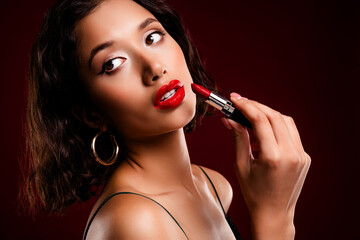 Obraz premium Elegant woman with stunning red lips applying lipstick in a glamorous fashion close-up