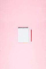 Blank white open spiral notebook with red pencil on soft pink background with wide copy space for planning, notes, wish lists, creative layouts and minimal design projects.