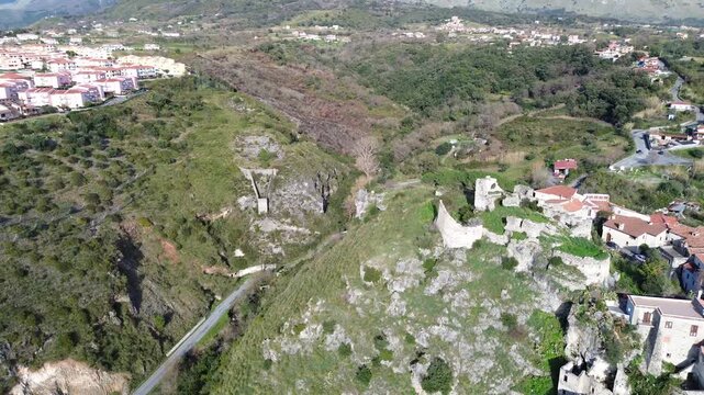Cinematic aerial orbital view of an ancient Norman castle in Scalea southern Italy revealing the vast Lao River valley with blue sea and lush green mountains