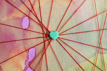Heart at the meeting point of several paths traced with a red thread, background with watercolor...