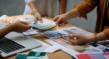 Designers collaborate over color swatches and a laptop during a session