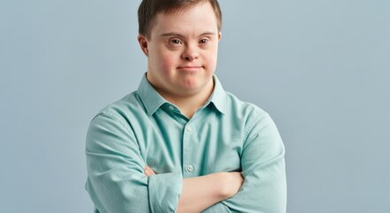 Man with Down syndrome standing with arms crossed against a plain background
