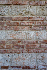 Detailed texture of an old red brick wall showing wear, surface flaking, and weathered mortar. A natural, realistic background for architectural or design applications.