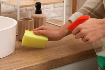 Female hands with sponge cleaning table in bathroom, closeup