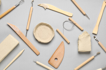 Set of sculptor tools and clay on grey background
