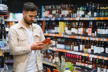 Man choosing bottle of wine in supermarket alcohol aisle